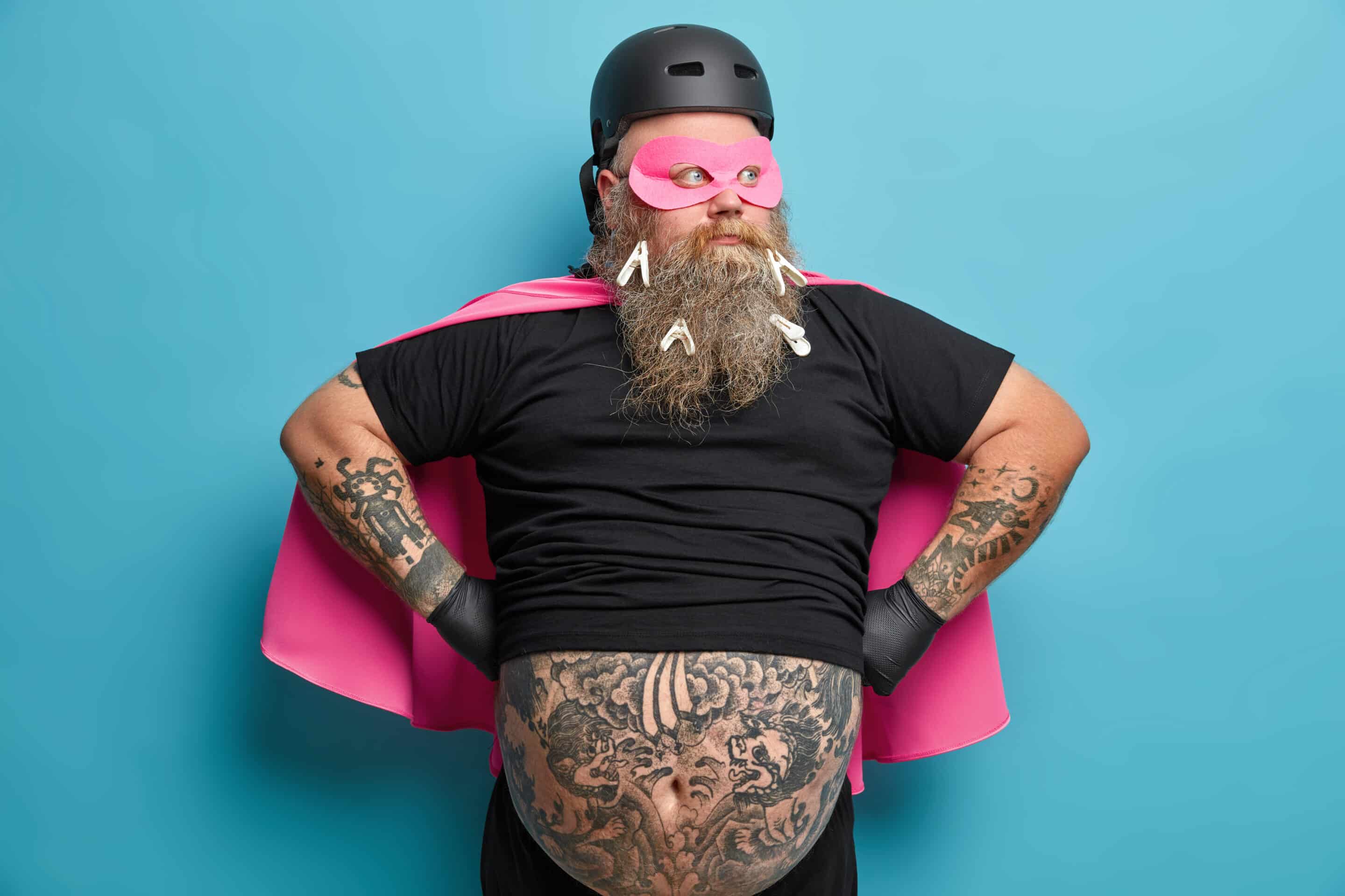 Bearded man in make-shift super-hero outfit, with tattooed belly poking out of his t-shirt