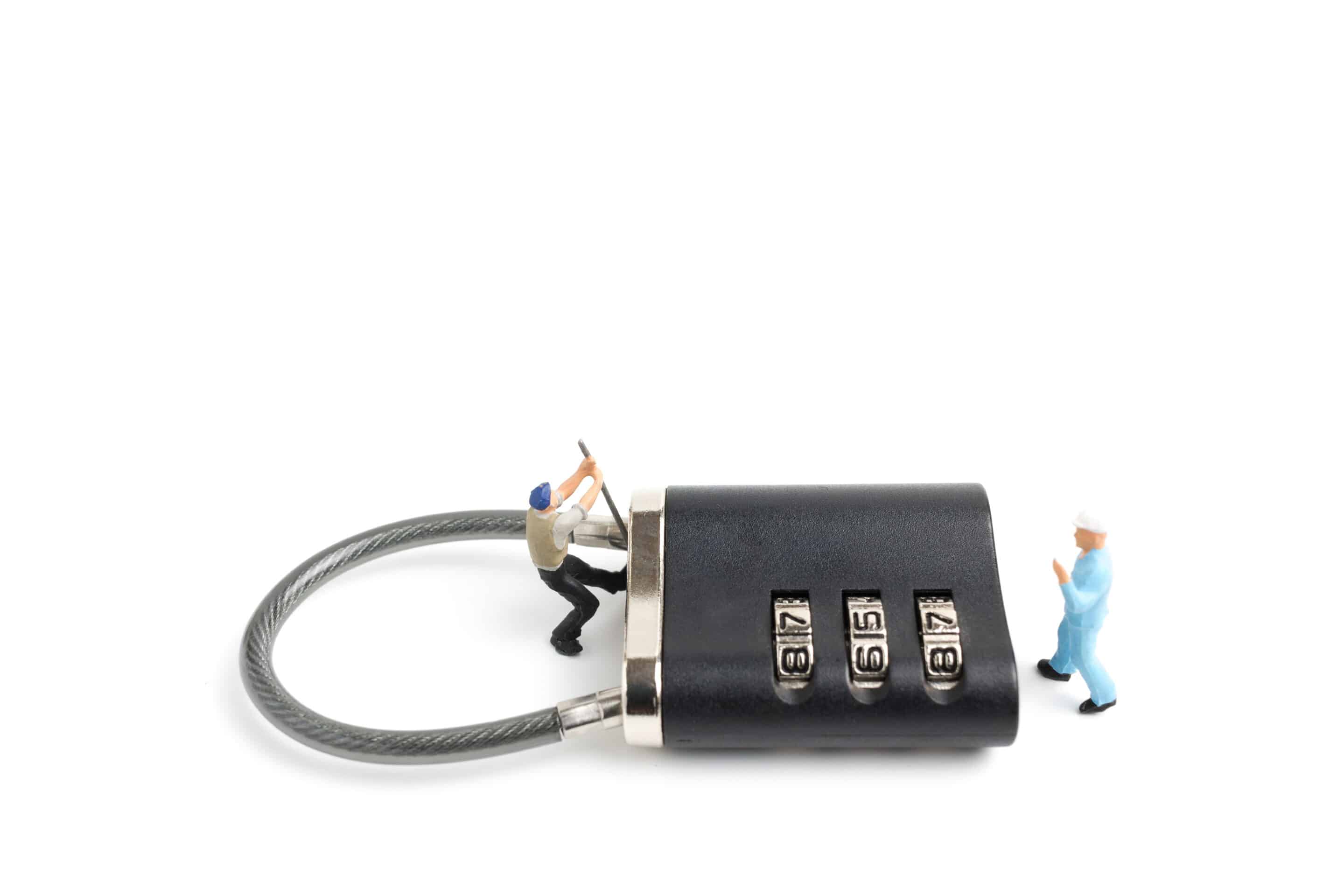 Angry CEO in tension trying to manage an organizational crisis in a boardroom 2 minature figures trying to break into a combination lock lying on white background