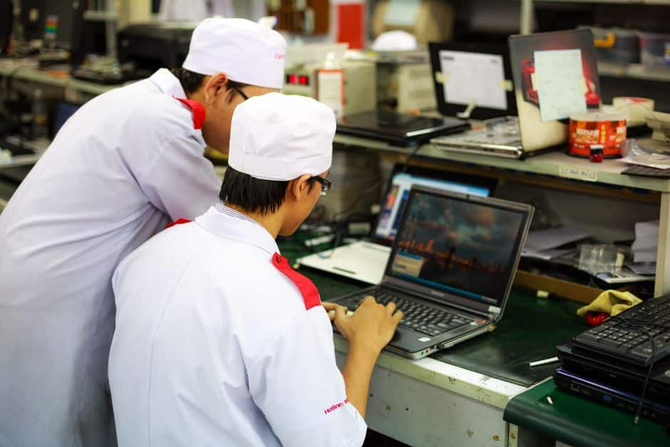 A plant manager reviews IT infrastructure for growing businesses on a laptop inside a modern UK manufacturing facility.