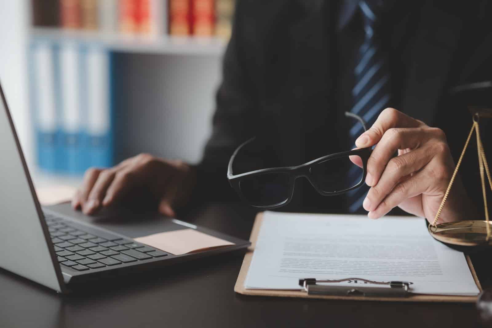 A conveyancing practice manager reviewing SRA compliance for law firms on a laptop at a tidy office desk