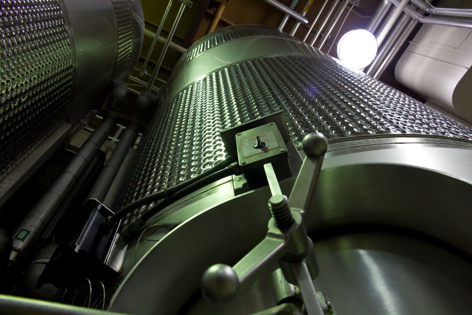 Rows of green glass bottles on an automated production line in a factory setting.