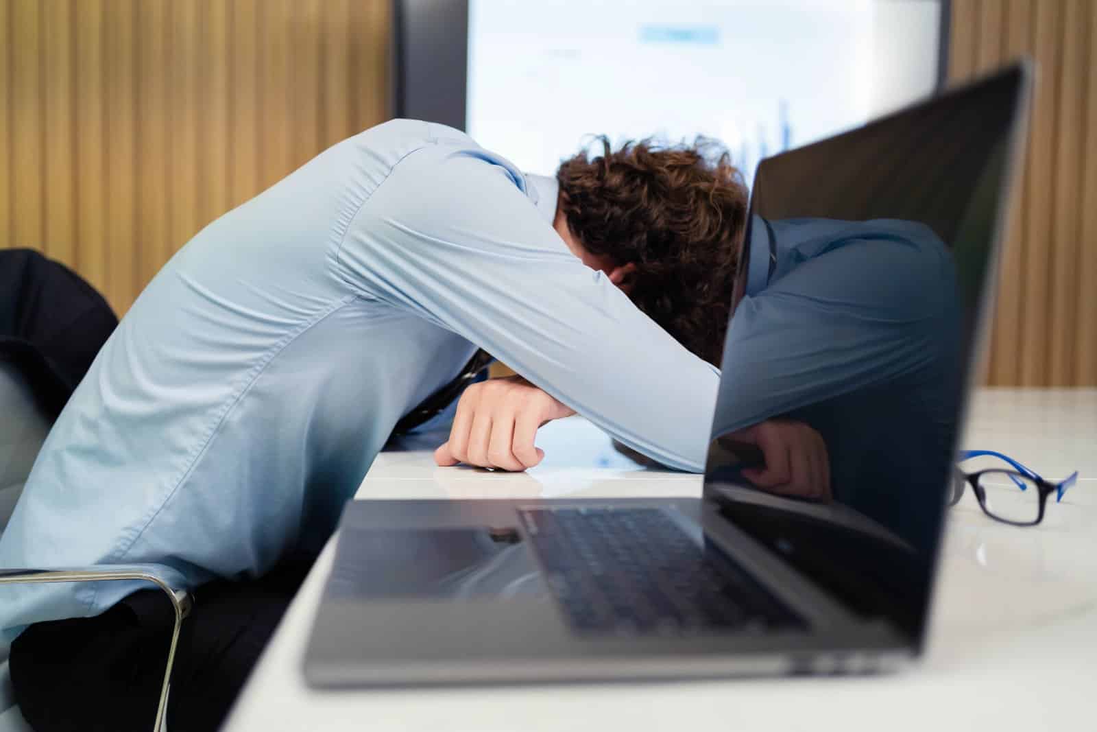 Man asleep at desk with laptop in front of him